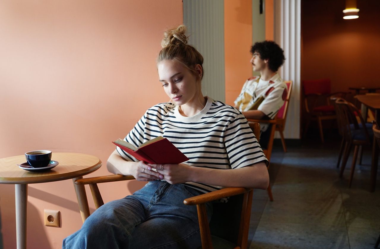Young woman reading a book in a stylish café with a warm and inviting atmosphere.