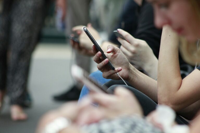 Des mains scrollant sur des écrans de smartphone, symbole de l'homme connecté isolé des autres